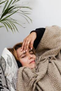 Vermoeide vrouw met pcos klachten liggend onder een dekentje