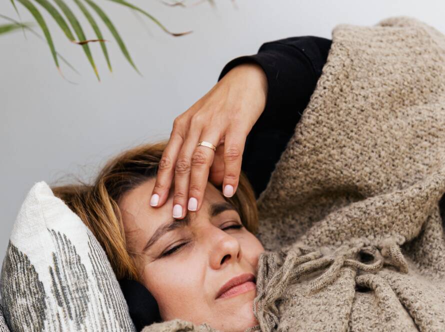 Vermoeide vrouw met pcos klachten liggend onder een dekentje