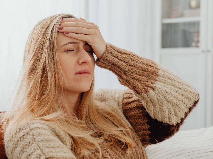 Vermoeide vrouw met blond haar op de bank met een gebreide trui