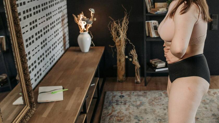 Vrouw in ondergoed die op de weegschaal gaat stappen.